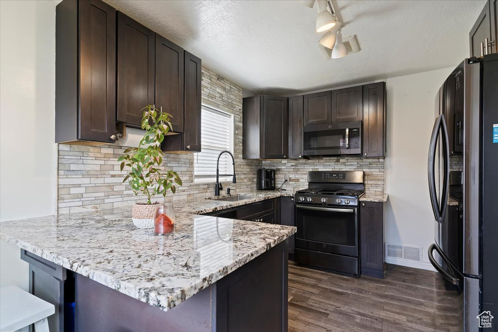 Kitchen with visible vents, black fridge, stainless steel microwave, a sink, and range with gas stovetop