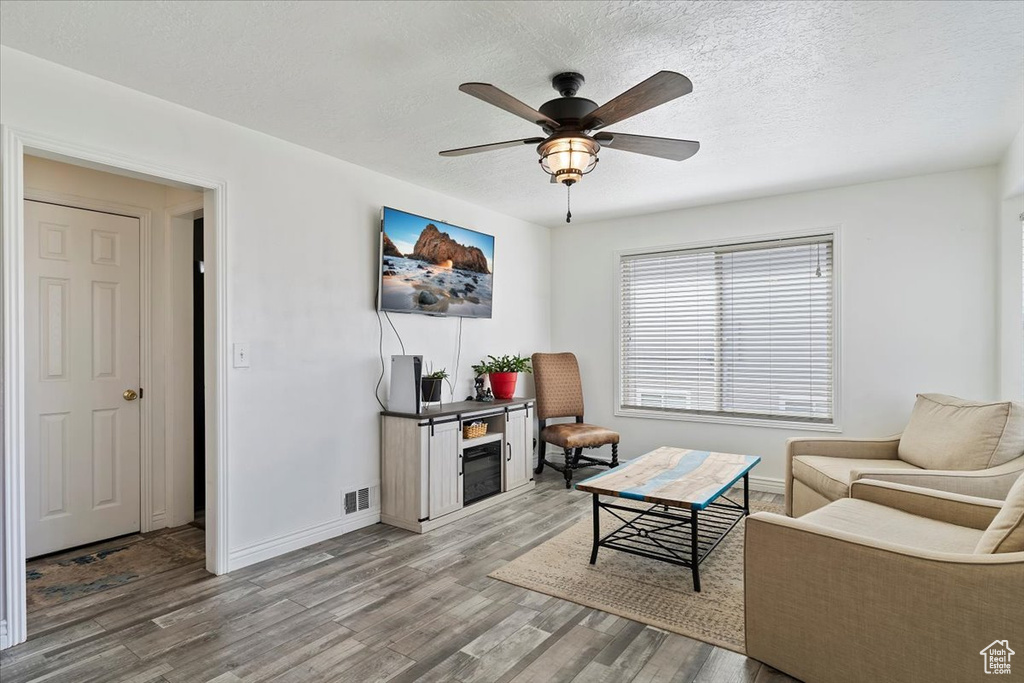Living area featuring ceiling fan, visible vents, baseboards, and wood finished floors