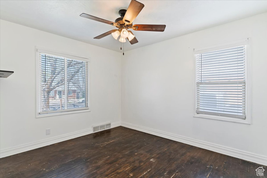 Unfurnished room with ceiling fan, dark wood-style flooring, baseboards, and visible vents