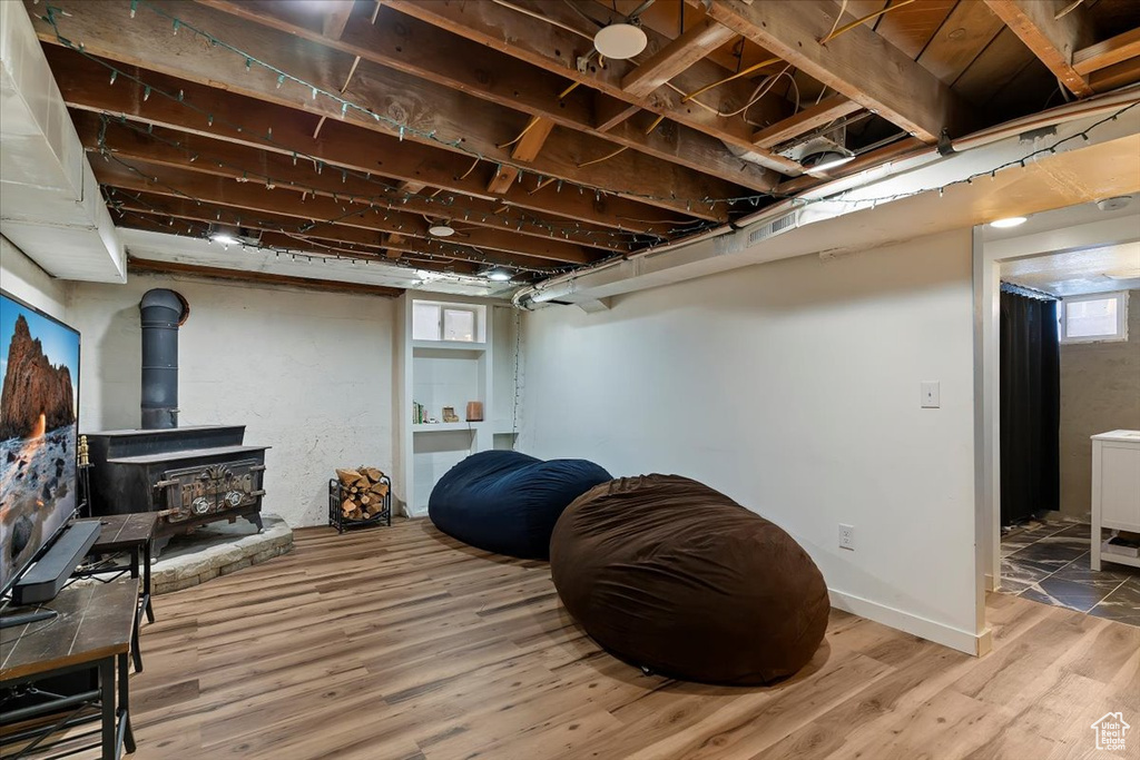 Below grade area with wood finished floors, a wood stove, and a healthy amount of sunlight