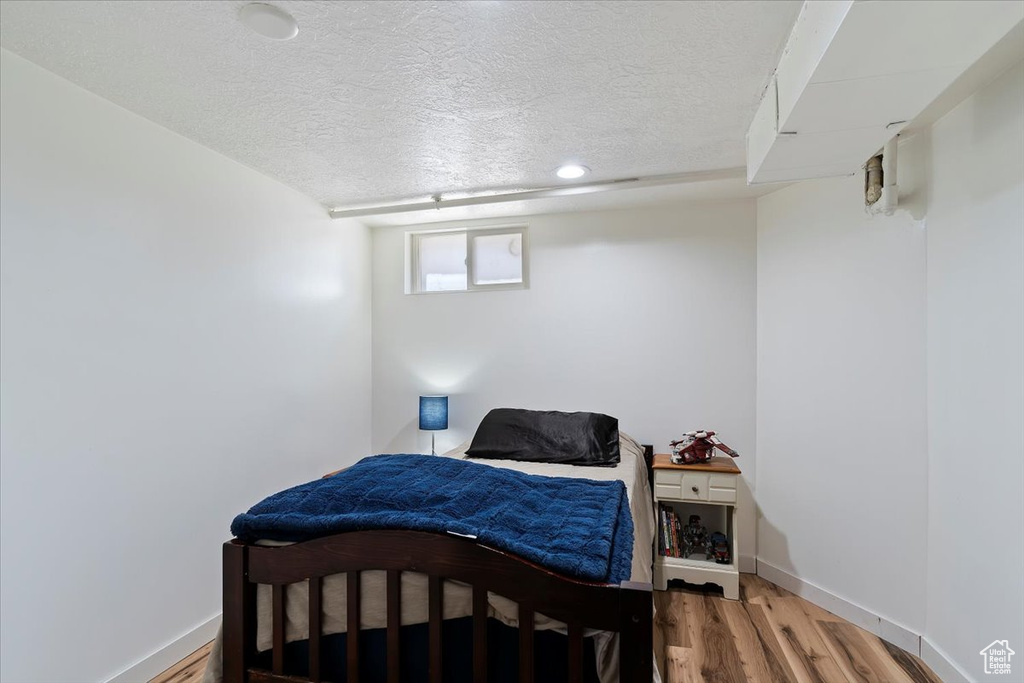 Bedroom featuring a textured ceiling, wood finished floors, and baseboards