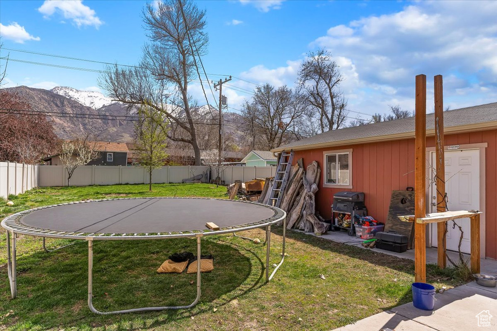View of yard with a mountain view, a fenced backyard, and a trampoline