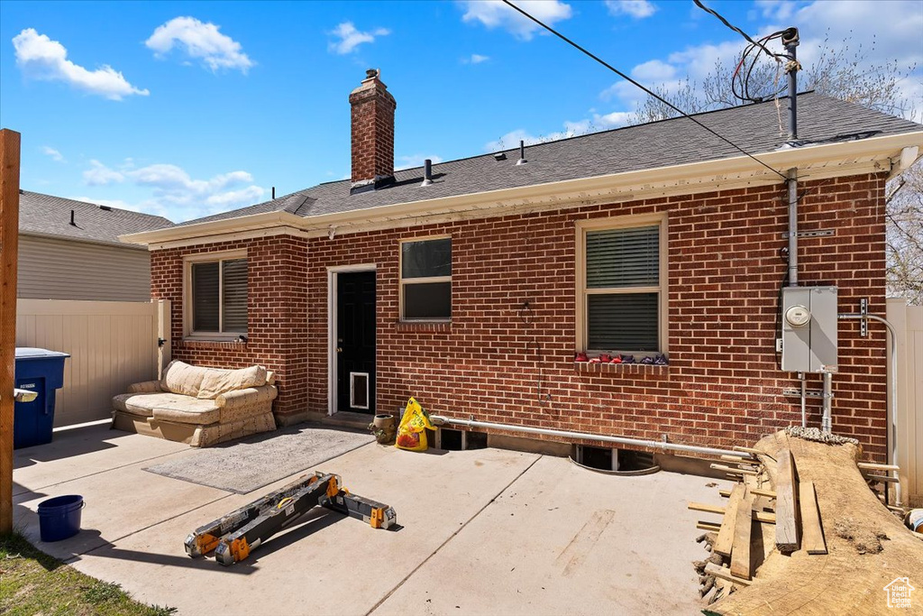 Rear view of property featuring a patio, fence, and brick siding