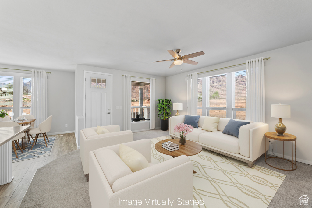 Living room with baseboards, ceiling fan, and a wealth of natural light