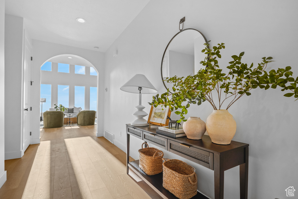 Corridor featuring baseboards, recessed lighting, visible vents, arched walkways, and wood finished floors