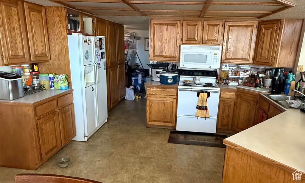 Kitchen featuring light countertops, a sink, white appliances, and brown cabinetry