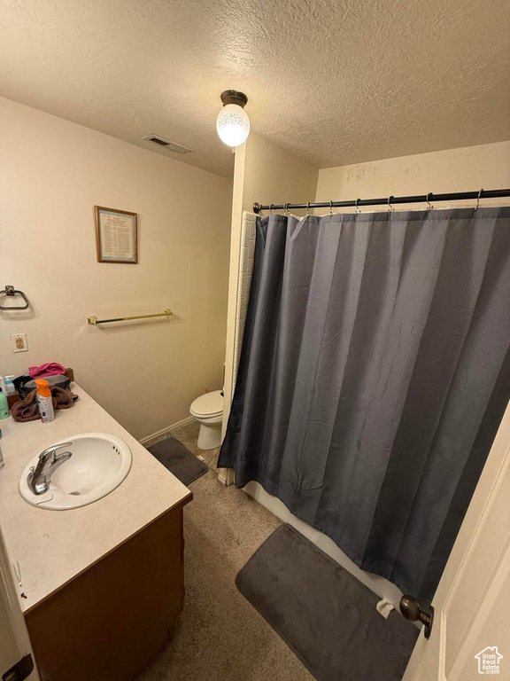 Bathroom with visible vents, a shower with shower curtain, toilet, a textured ceiling, and vanity