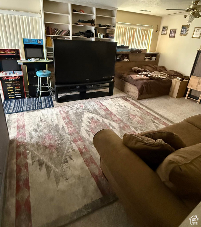 Carpeted living area featuring a ceiling fan