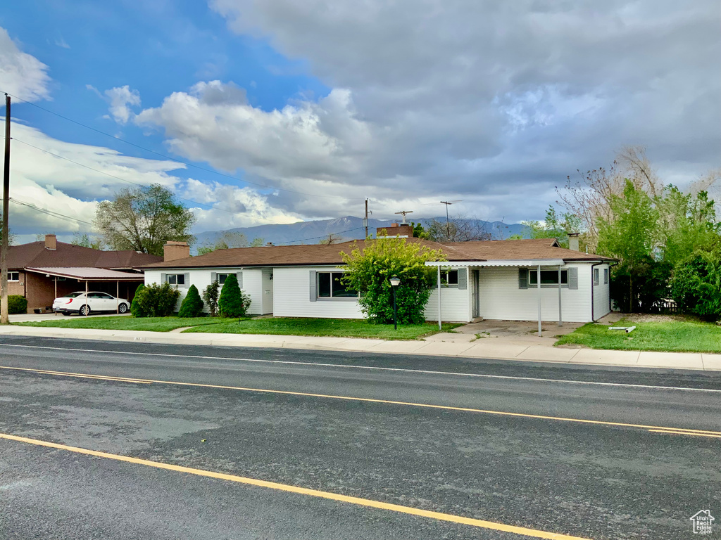 Ranch-style home with a mountain view, a chimney, and a front lawn