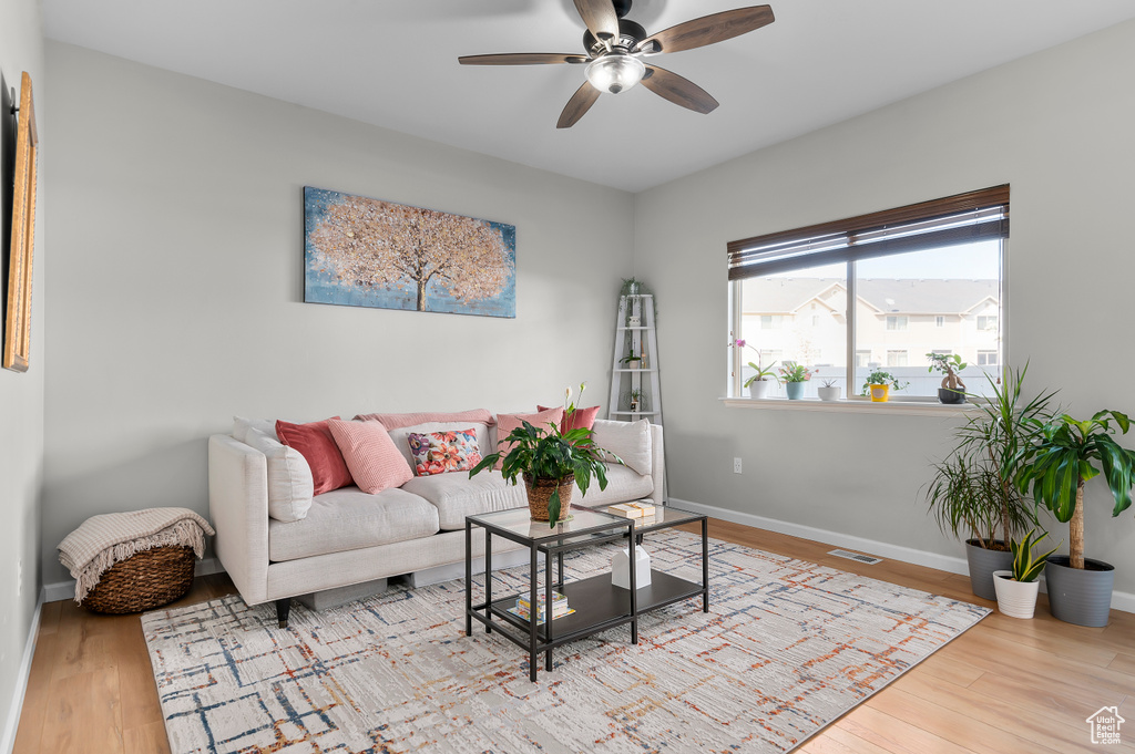 Living area featuring visible vents, baseboards, a ceiling fan, and wood finished floors