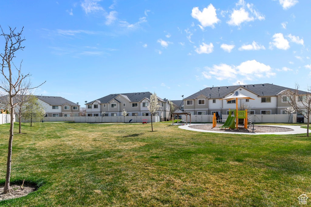View of home's community featuring a yard, fence, a playground, and a residential view