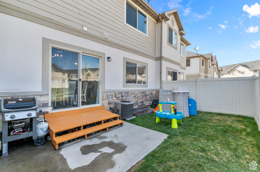 View of yard featuring a patio area, central AC unit, fence, and a residential view
