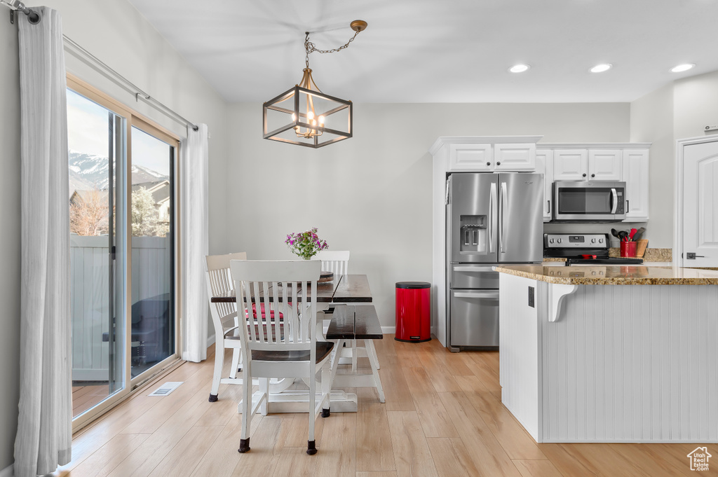 Kitchen with a chandelier, recessed lighting, white cabinetry, light stone countertops, and appliances with stainless steel finishes