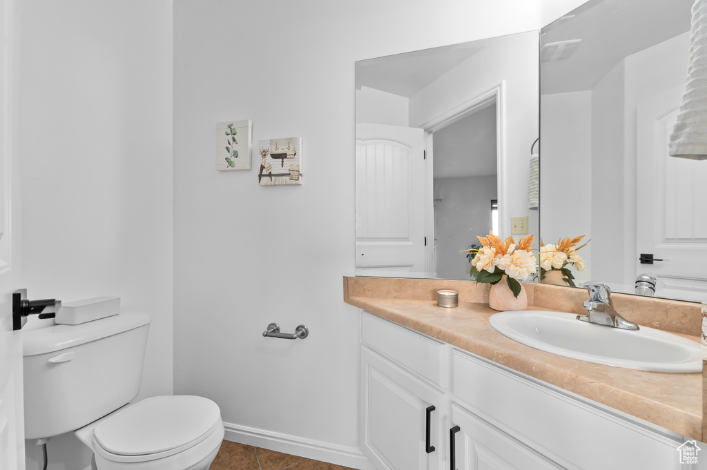 Bathroom featuring tile patterned floors, vanity, baseboards, and toilet
