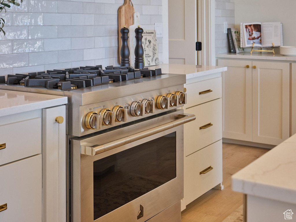 Room details with white cabinetry, high end range, and light stone counters