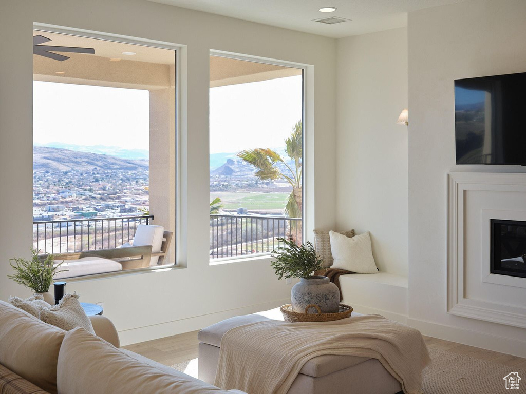 Living room featuring wood finished floors, baseboards, a ceiling fan, and a glass covered fireplace