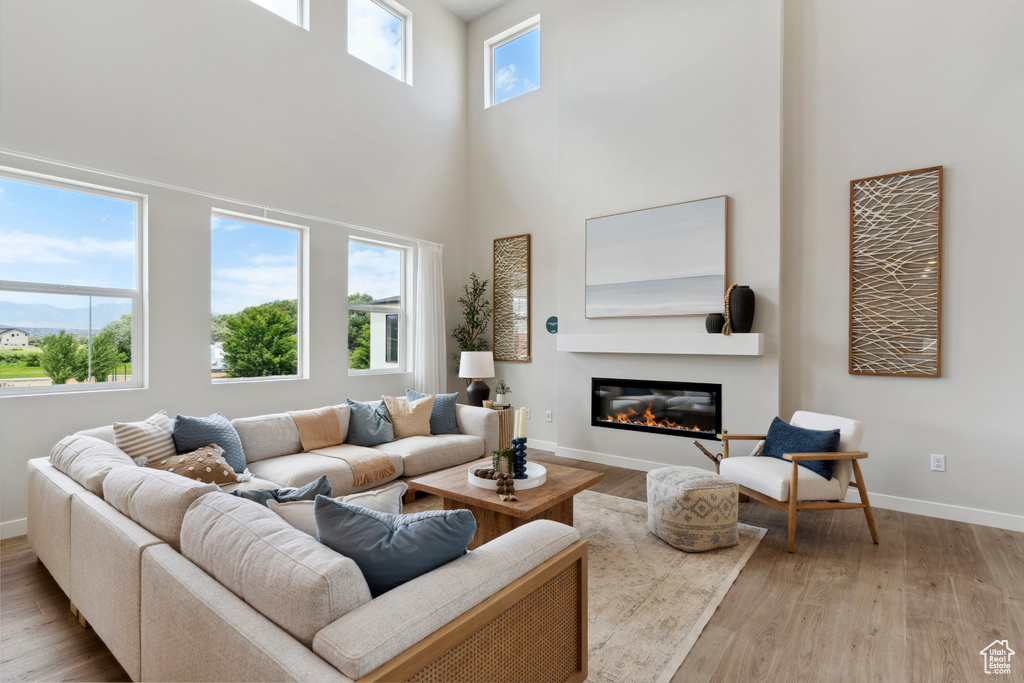 Living area featuring wood finished floors, a glass covered fireplace, and a towering ceiling