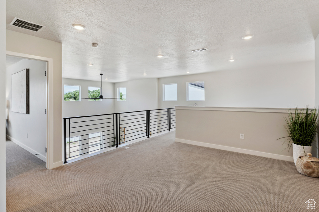 Empty room featuring light carpet, a textured ceiling, and recessed lighting