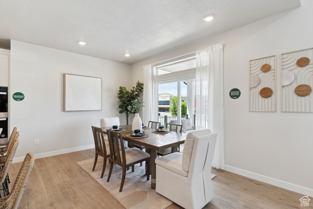 Dining area featuring light wood-style floors, a textured ceiling, and recessed lighting