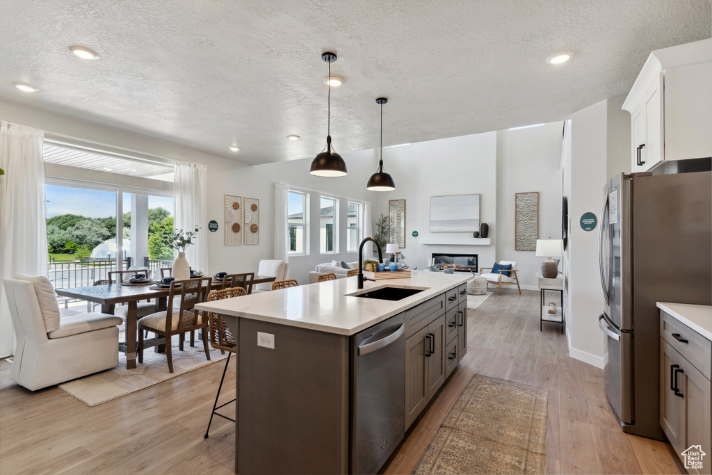 Kitchen featuring appliances with stainless steel finishes, open floor plan, a textured ceiling, light wood-style floors, and light countertops