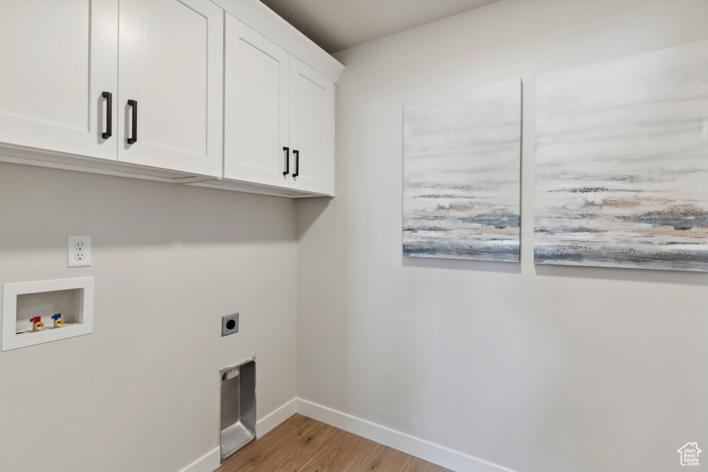 Washroom featuring cabinet space, light wood-style flooring, hookup for an electric dryer, and hookup for a washing machine