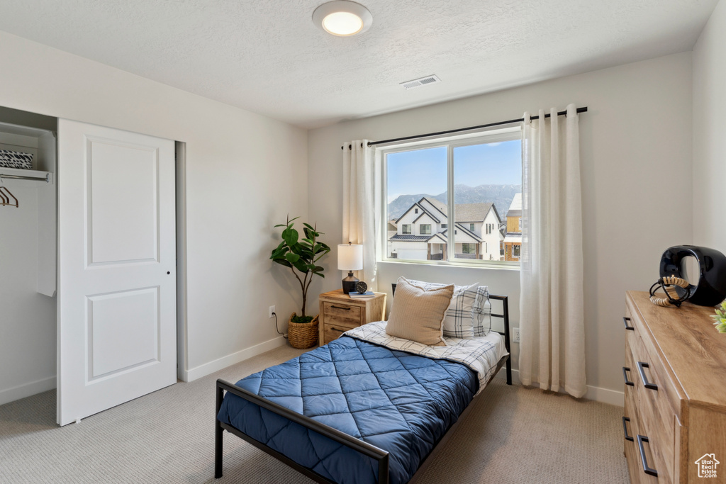 Bedroom with light carpet and a textured ceiling