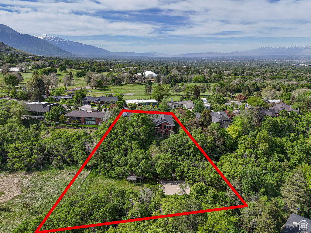 Aerial view of residential area with property parcel outlined and mountains