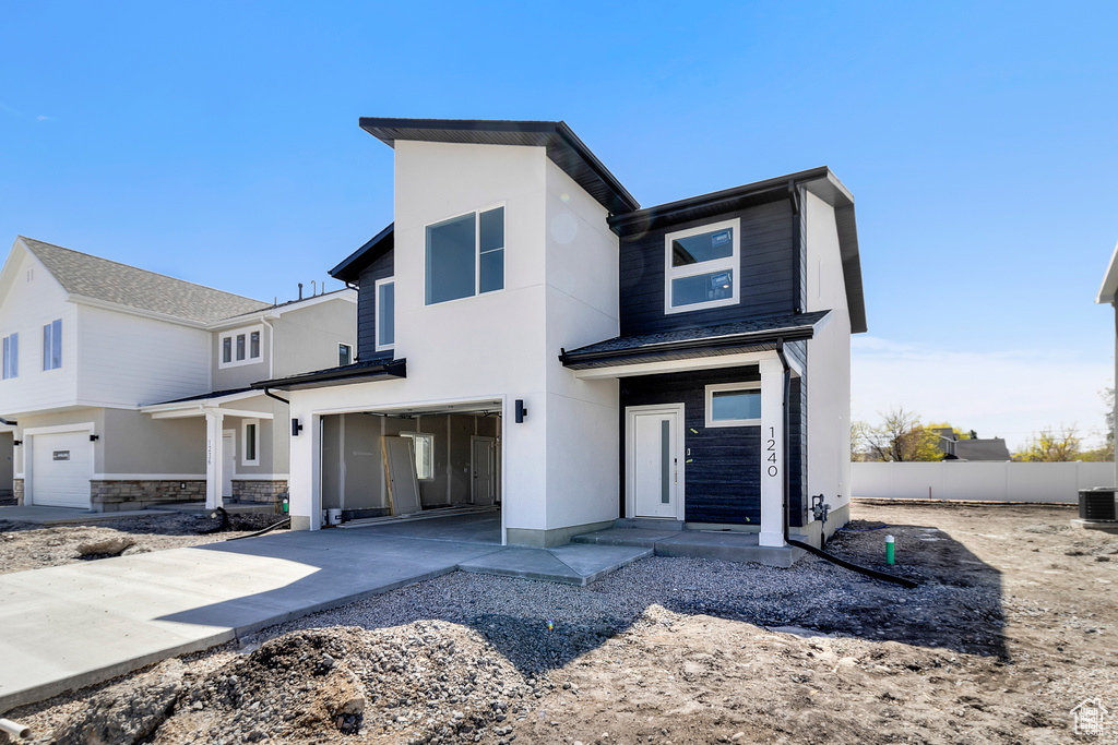 View of front facade with cooling unit, concrete driveway, stucco siding, an attached garage, and fence