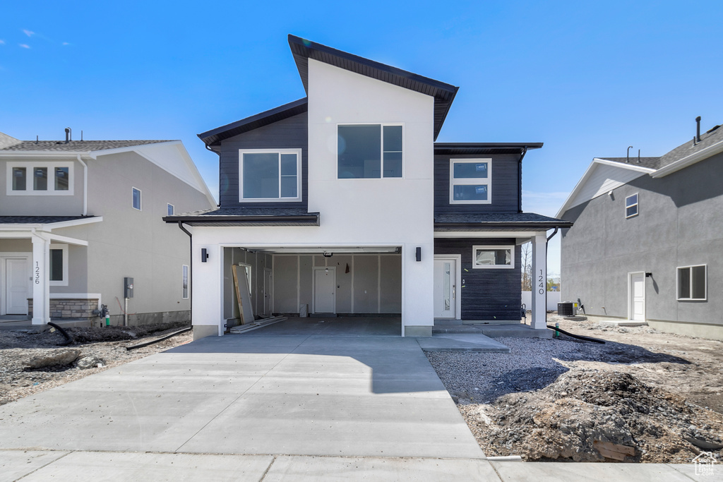 Contemporary house with concrete driveway, central AC unit, and a garage