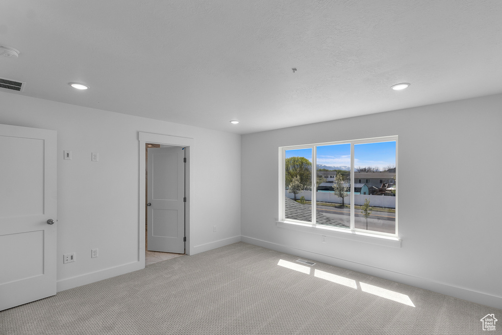 Carpeted spare room featuring baseboards, visible vents, and recessed lighting