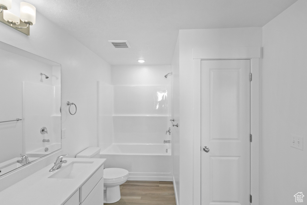 Bathroom with visible vents, bathing tub / shower combination, wood finished floors, and vanity