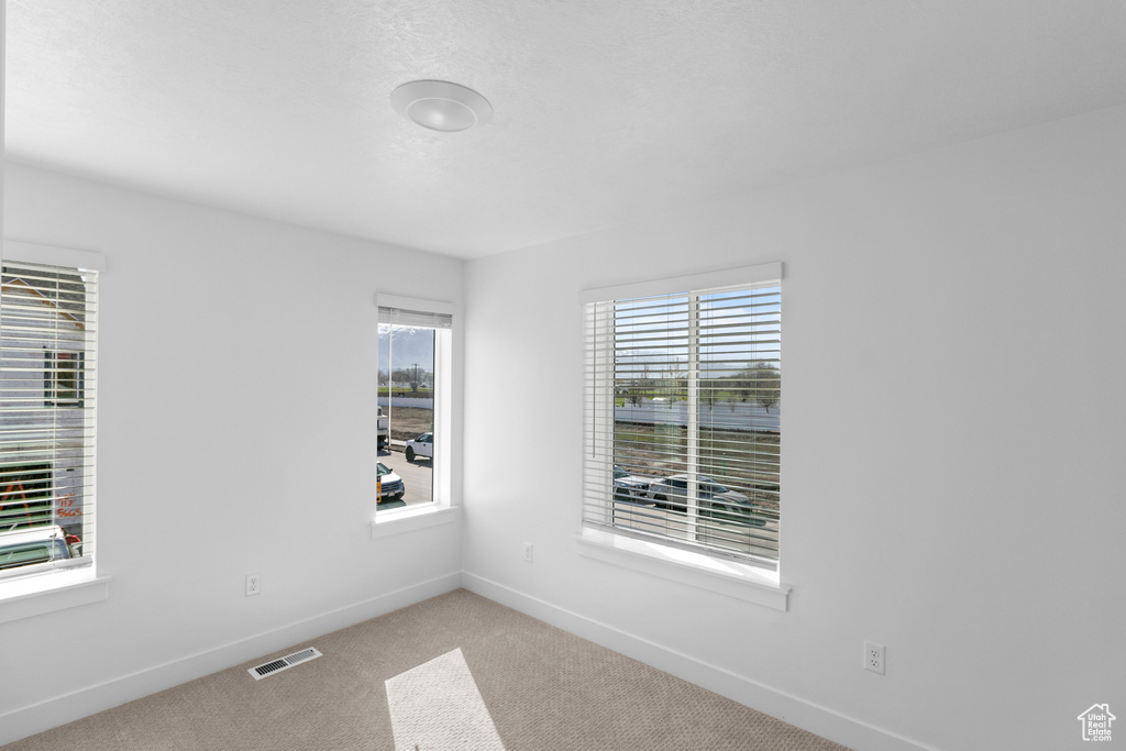 Unfurnished room featuring carpet, visible vents, and baseboards