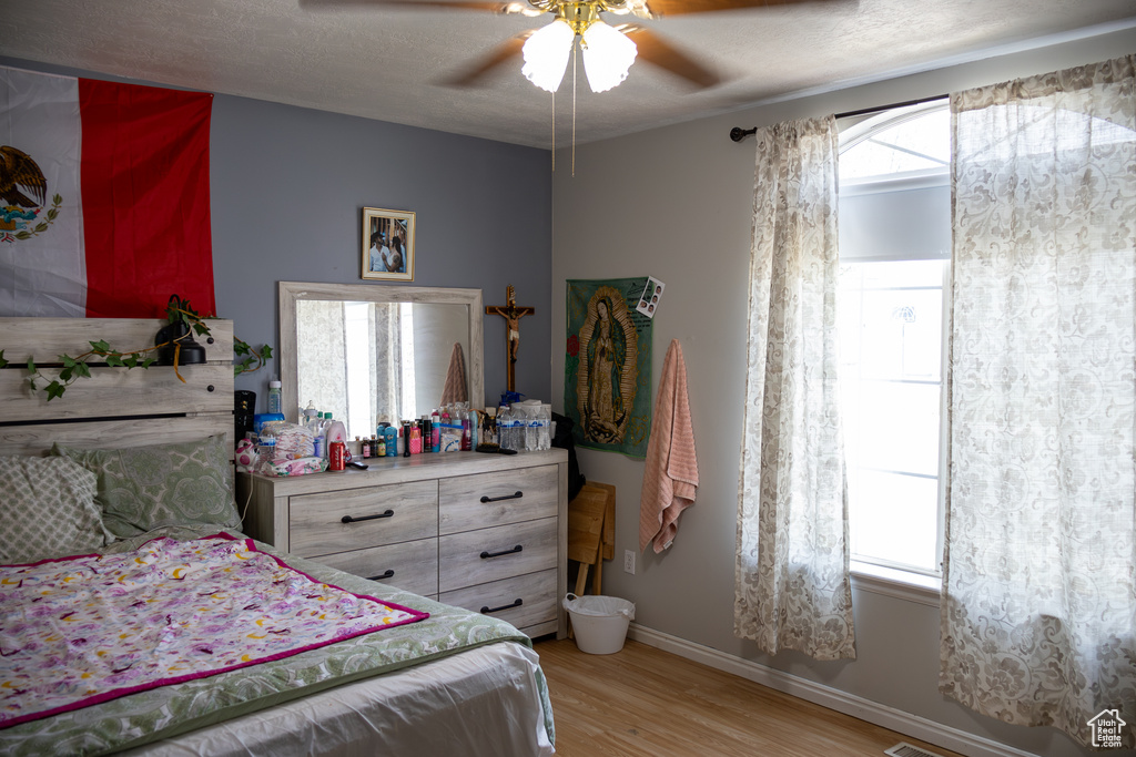 Bedroom with light wood finished floors, baseboards, and a ceiling fan