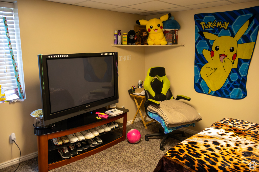 Bedroom featuring baseboards, a drop ceiling, and carpet