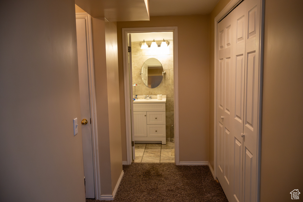 Corridor with light carpet, a sink, and baseboards