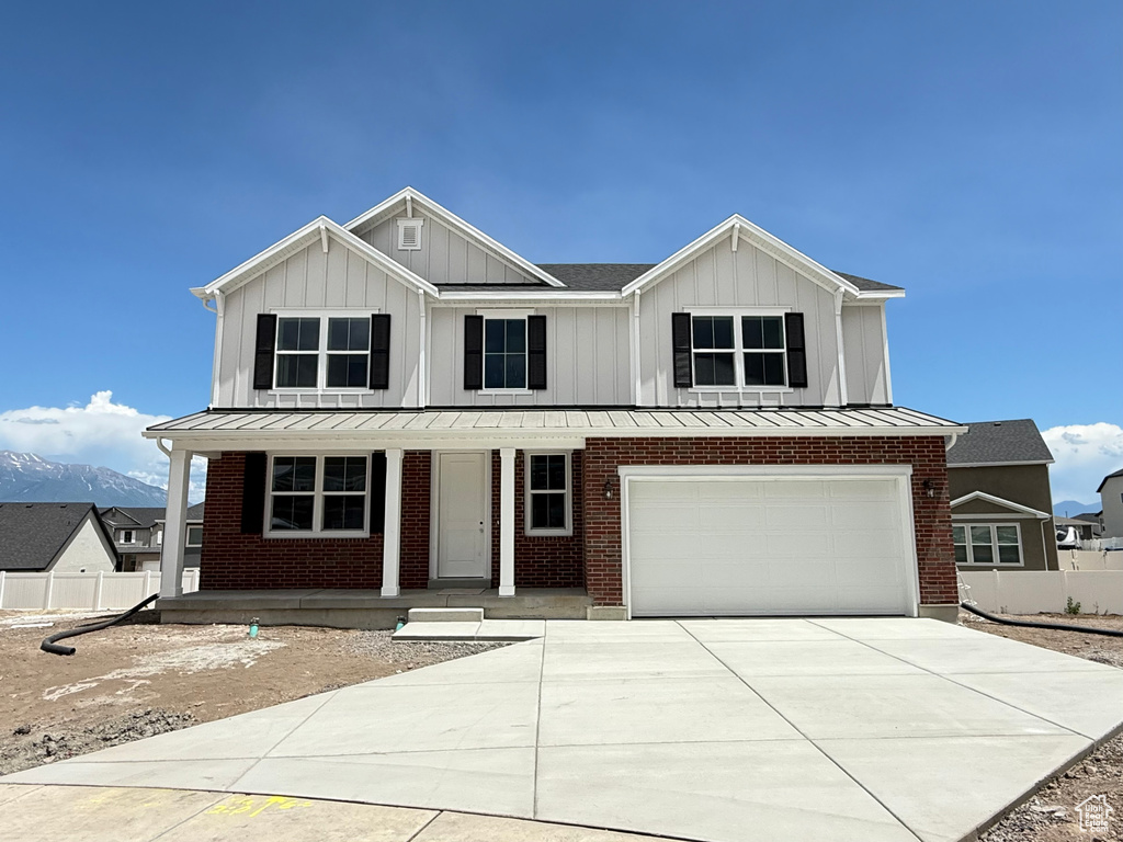 View of front of house with board and batten siding, a porch, concrete driveway, a garage, and a standing seam roof