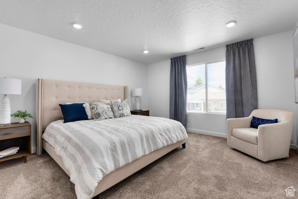 Carpeted bedroom featuring a textured ceiling, baseboards, visible vents, and recessed lighting