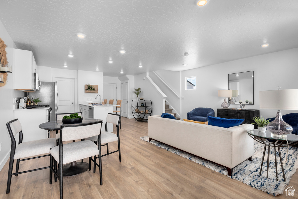 Living room featuring light wood-style floors, recessed lighting, a textured ceiling, and stairs