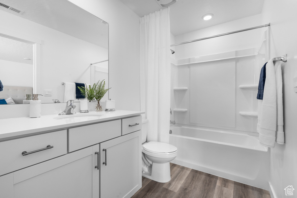 Bathroom with vanity, shower / tub combo with curtain, toilet, visible vents, and wood finished floors