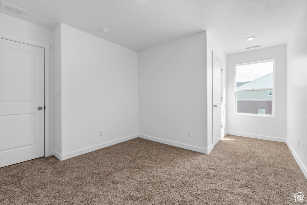 Carpeted empty room with baseboards and visible vents
