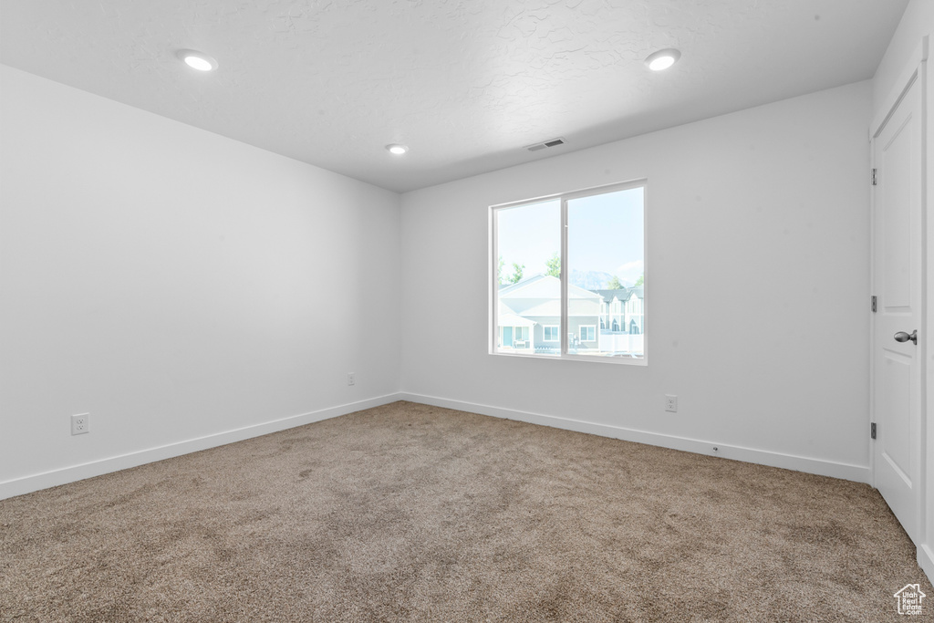 Carpeted spare room featuring baseboards, visible vents, and recessed lighting