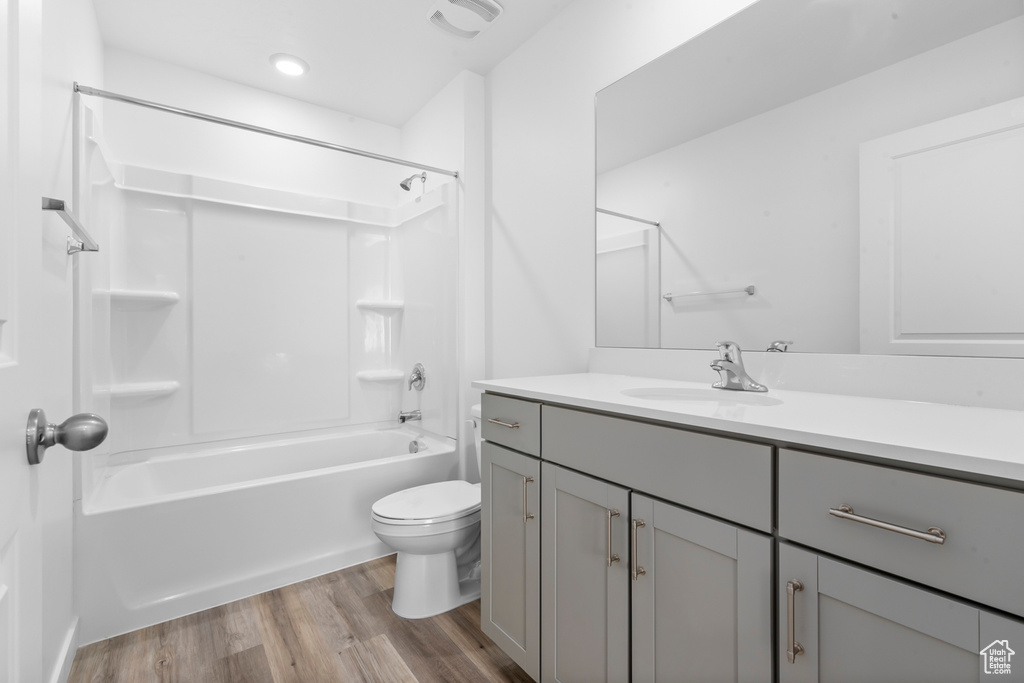 Bathroom featuring visible vents, toilet, vanity, wood finished floors, and shower / tub combination