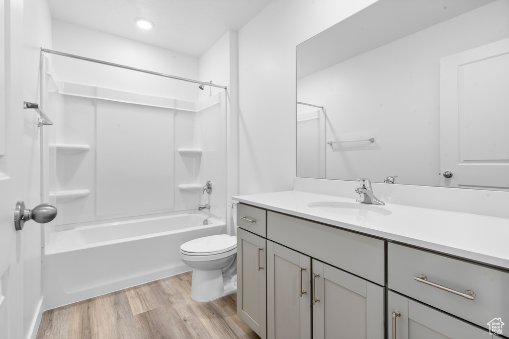 Full bath with washtub / shower combination, vanity, recessed lighting, toilet, and wood finished floors