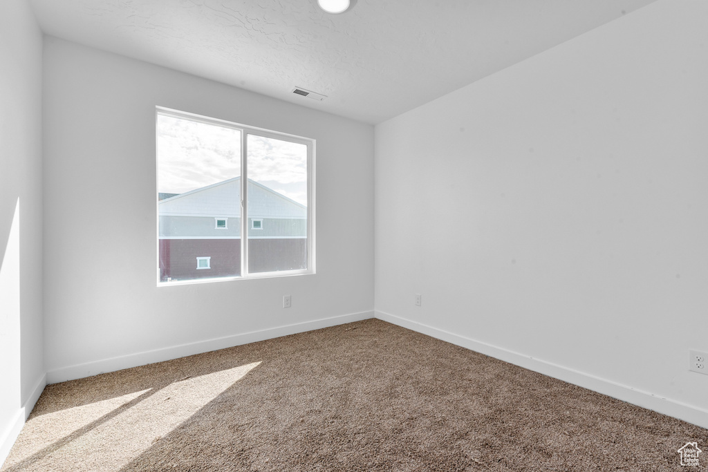 Empty room featuring baseboards, carpet, and visible vents