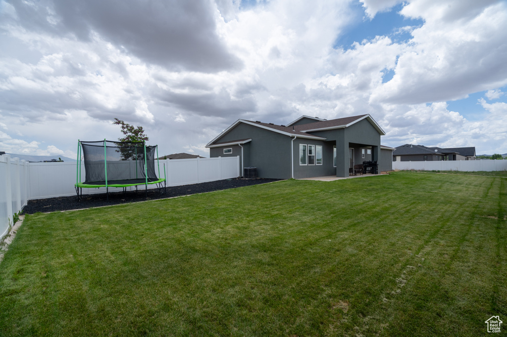 Rear view of house featuring stucco siding, a trampoline, and a patio area