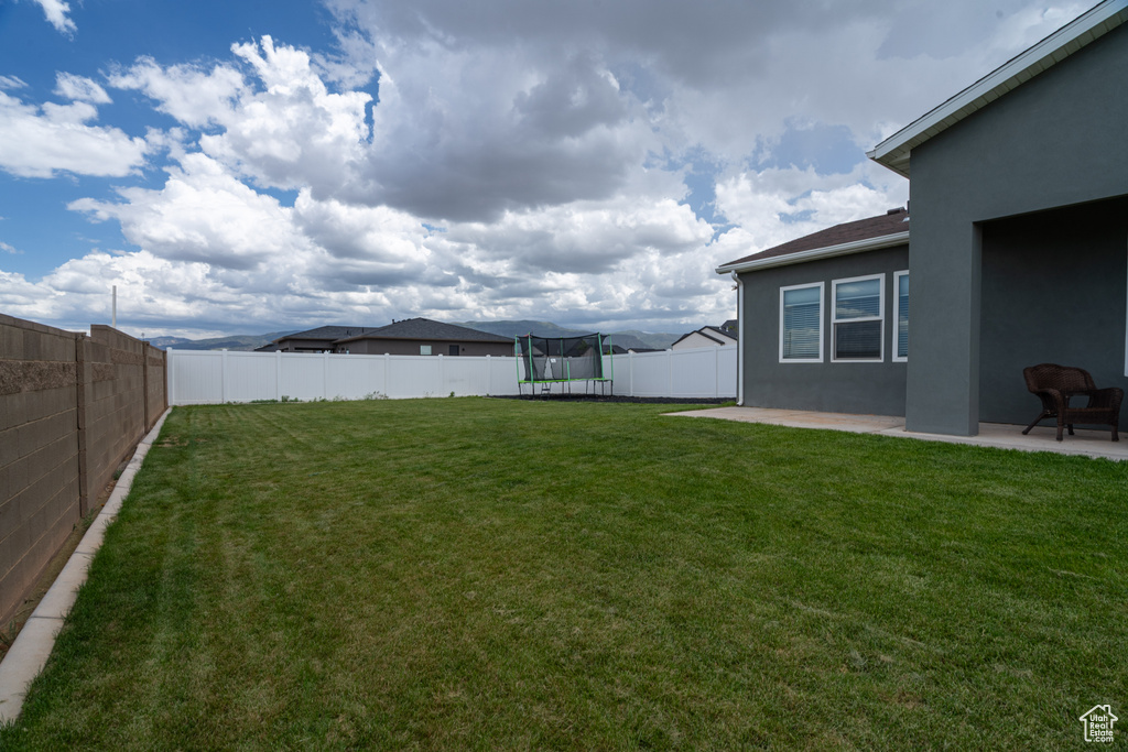 View of yard featuring a trampoline and a patio