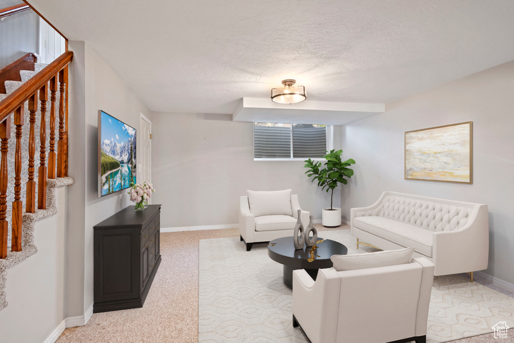 Living room featuring stairs, a textured ceiling, carpet flooring, and baseboards