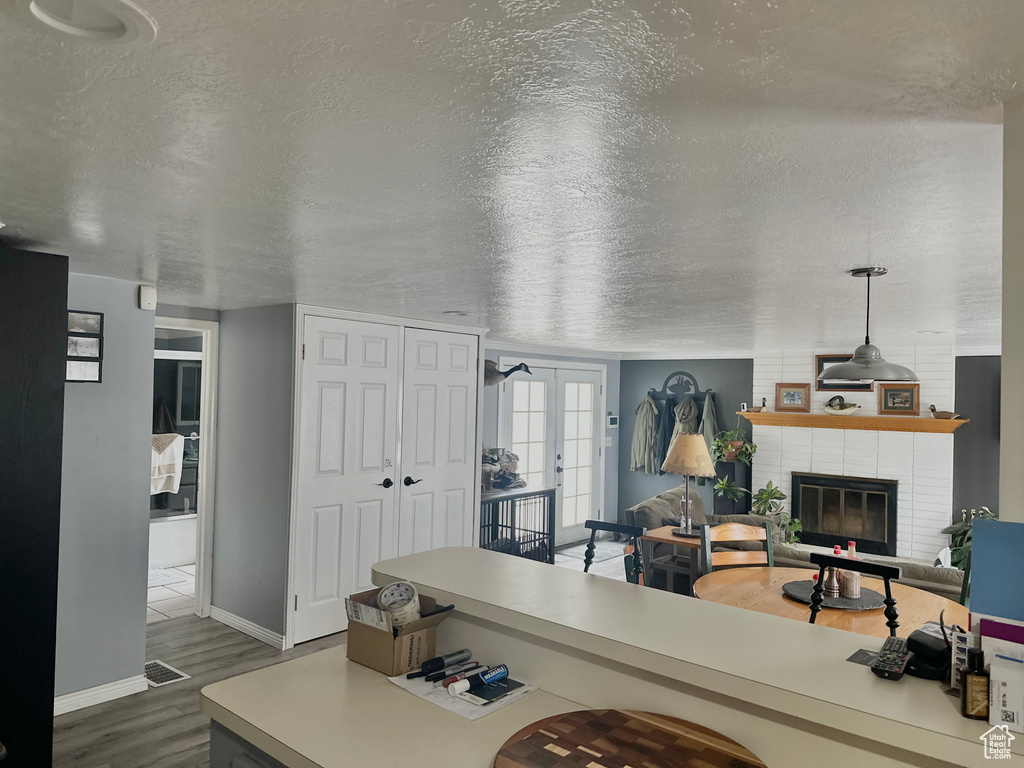 Living area with dark wood finished floors, baseboards, a brick fireplace, a textured ceiling, and french doors