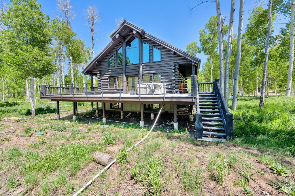 Rear view of property featuring log exterior, stairway, and a deck