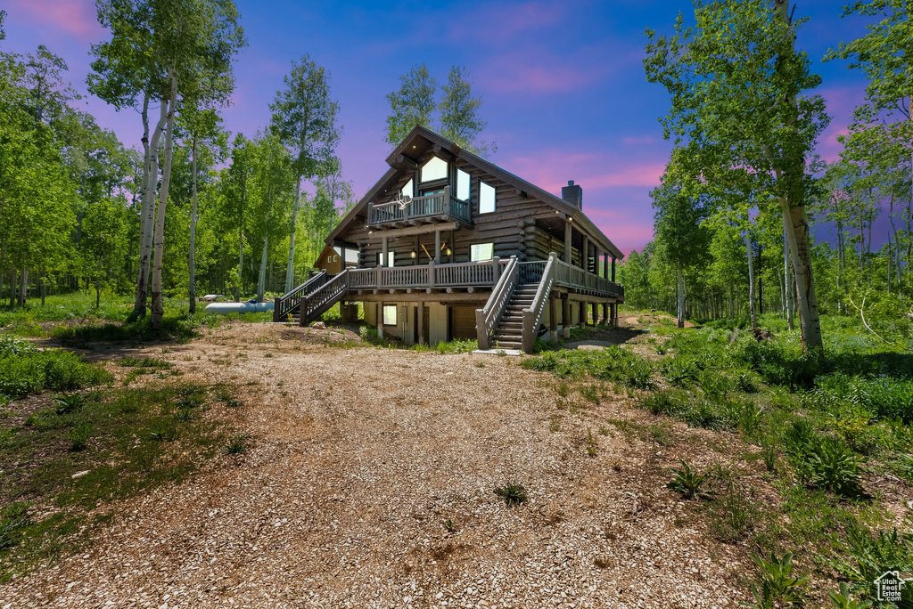 View of front facade with stairs, a chimney, a deck, and log exterior